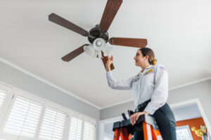 Mister Sparky employee installing ceiling fan to help Lakeland homeowner save energy