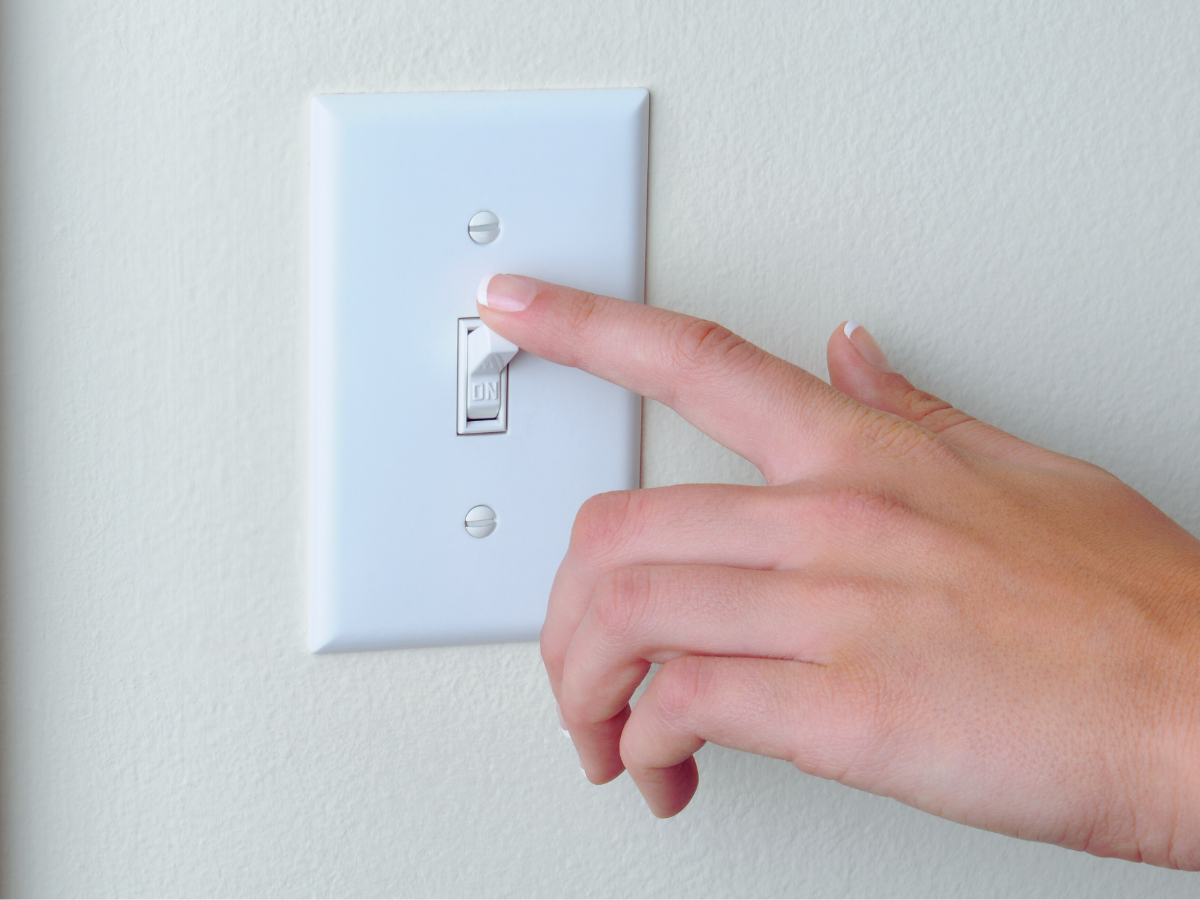 Hand turning on light switch